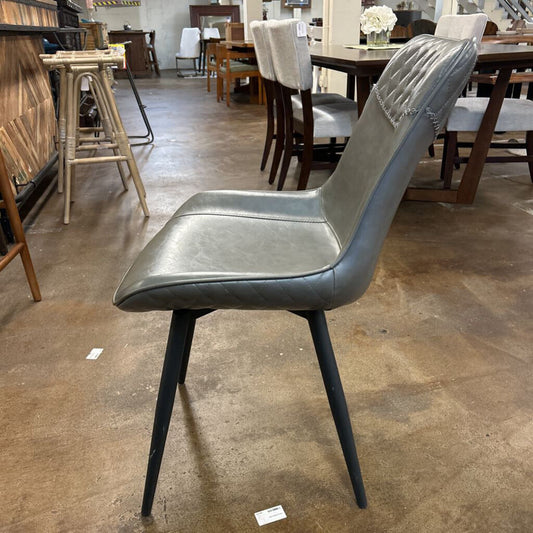 Gray chair with black legs on a brown floor in a furniture store