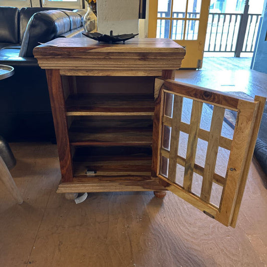 Wooden side table with an open cabinet door on a wooden floor.