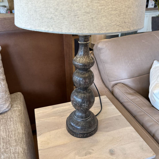Decorative lamp with a textured base on a wooden table in a living room setting.