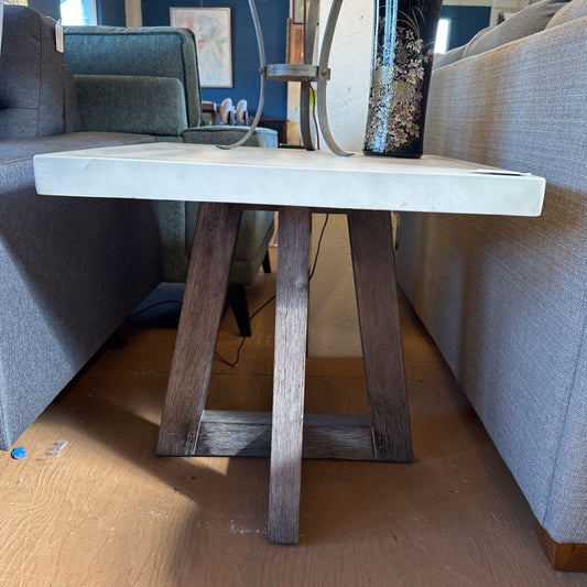 Small wooden table with a concrete top in a living room setting.
