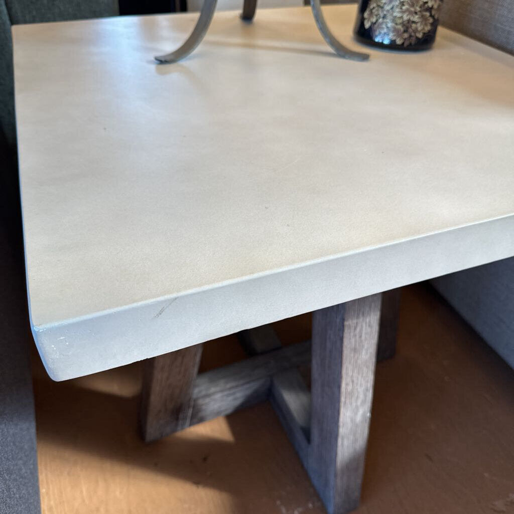 Close-up of a table with a concrete top and wooden legs.