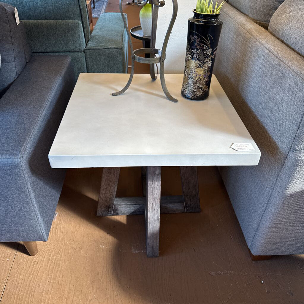 Small square table with a white top and wooden legs between two gray sofas.