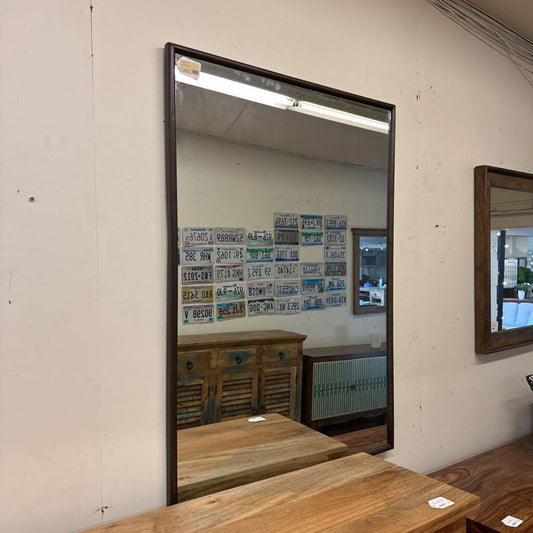 Large mirror on a wall with a reflection of a room with tables and chairs.