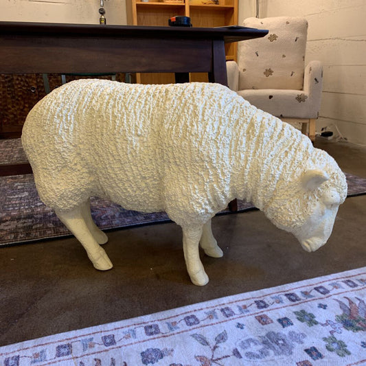 White sheep sculpture in a room with a table and chair.