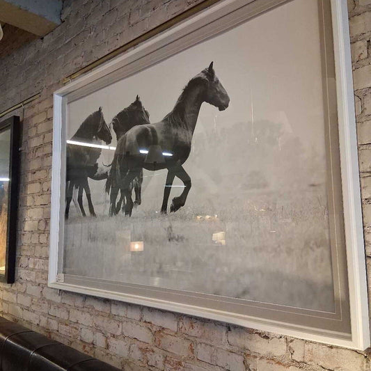 Framed artwork of horses on a brick wall