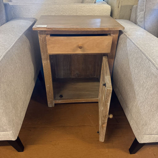 Wooden side table with a drawer next to a gray sofa.