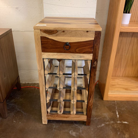 Wooden wine rack with a drawer against a white wall.