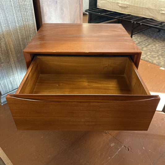 Wooden drawer unit with an open drawer on a wooden floor.