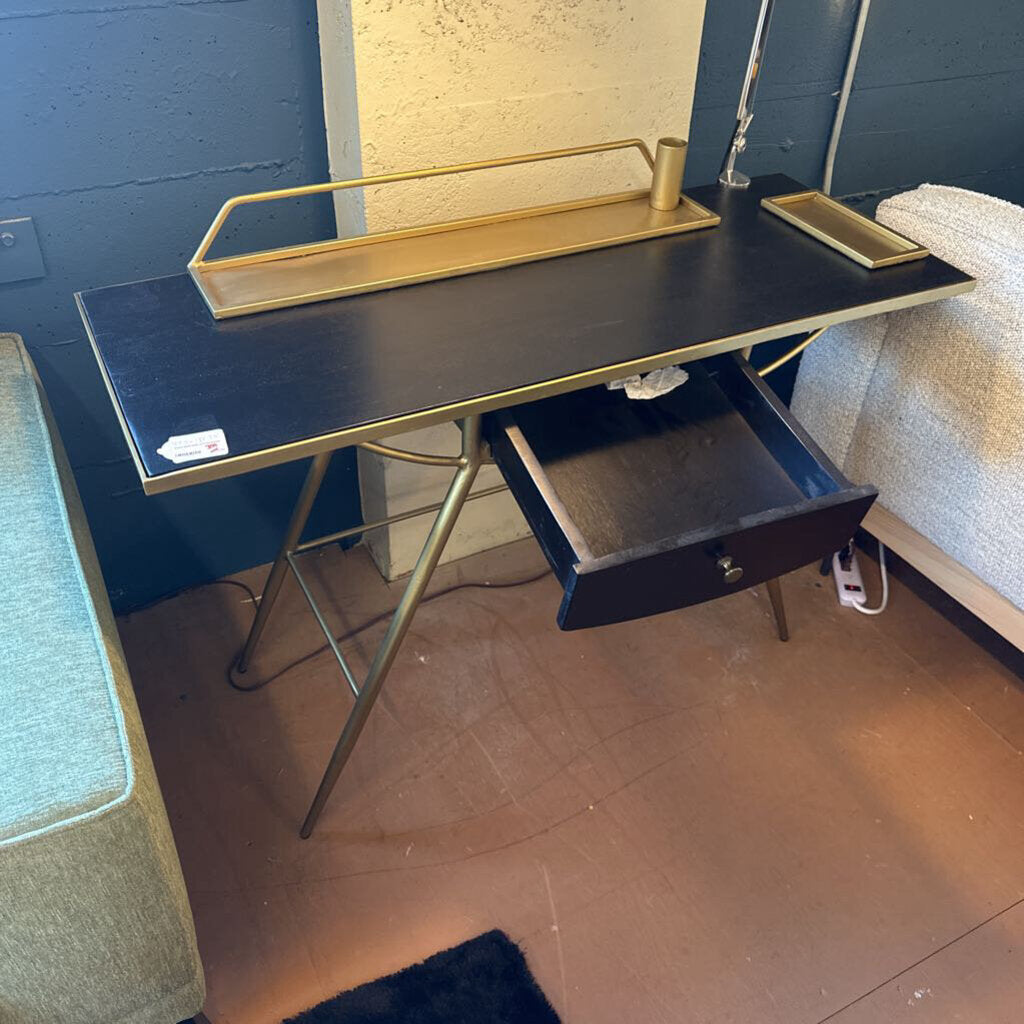 Black desk with gold accents in a room with blue walls and a carpeted floor.