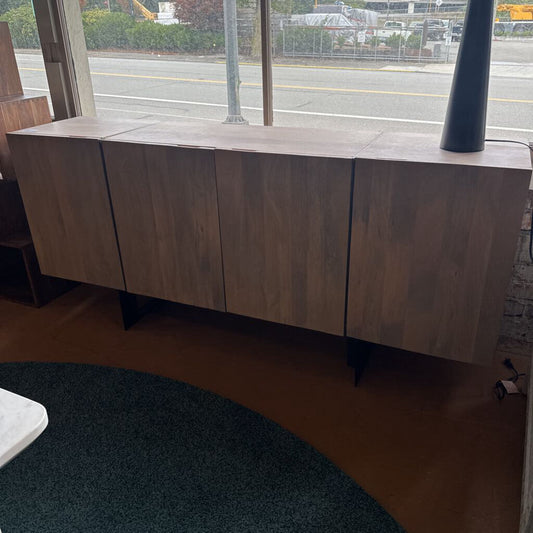 Wooden cabinet in a room with a window view of a road.