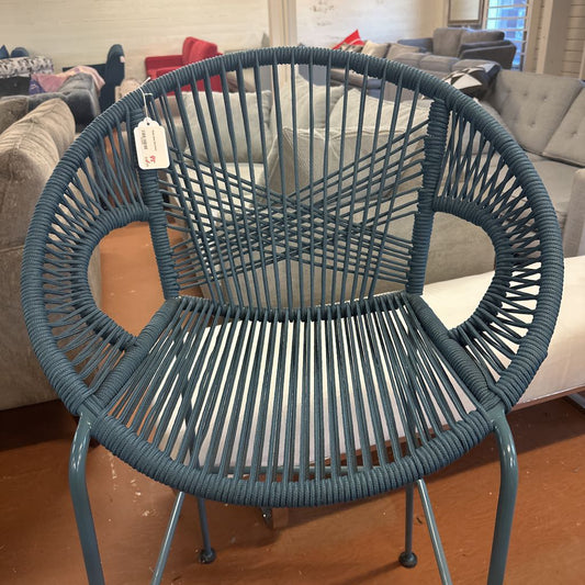 Blue wicker chair in a living room setting with furniture in the background