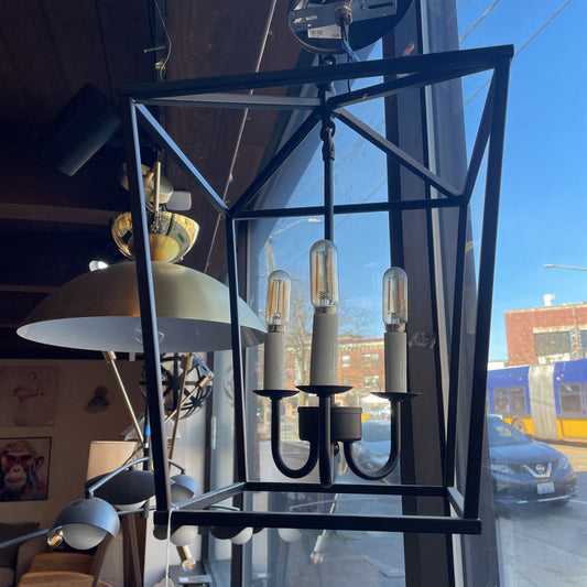 Modern black metal chandelier with glass shade in a store window