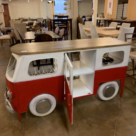 Red and white van-shaped table with wooden top in a room with tables and chairs.