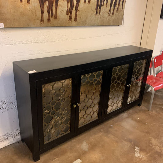 Black cabinet with decorative glass panels against a wall with a painting of horses.