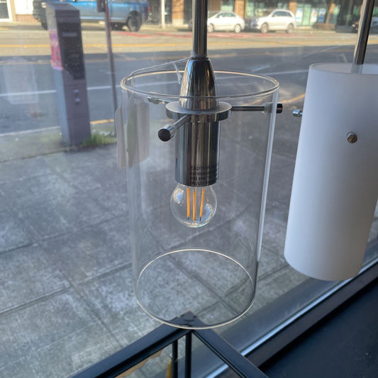 Clear glass pendant light with visible bulb inside, outdoors.