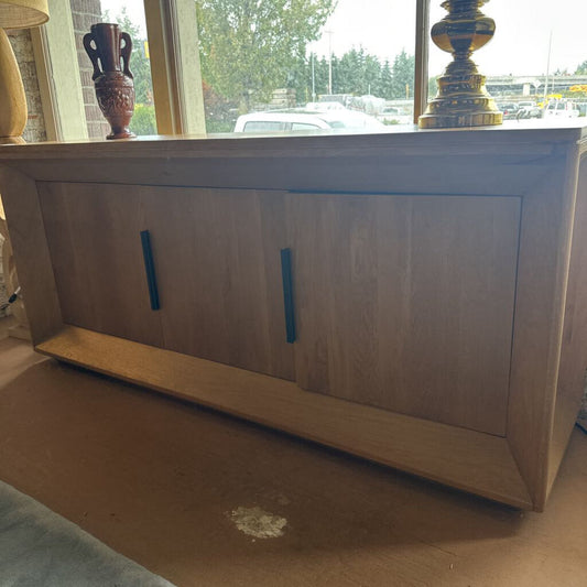 Wooden cabinet with two doors and a shelf on a wooden floor.