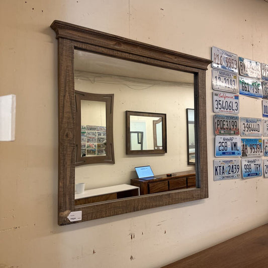 Wooden-framed mirror on a wall with license plate decorations