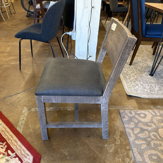 Gray chair with a cushioned seat in a room with other furniture.