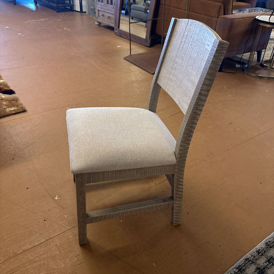Chair with a textured backrest and seat on a brown floor.