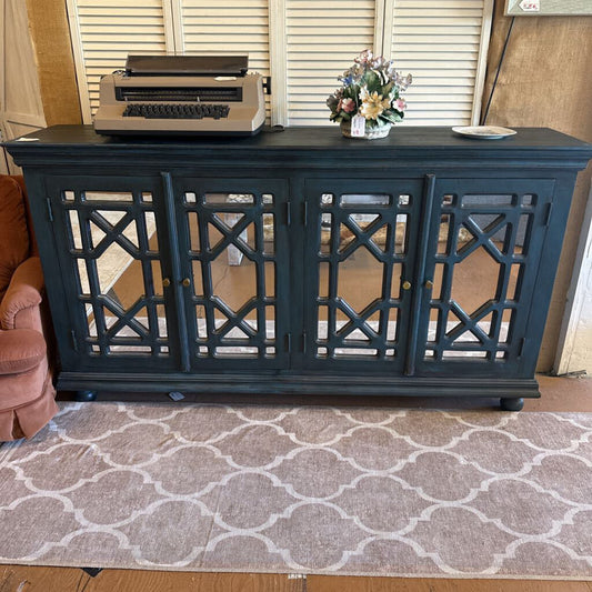 Dark blue cabinet with decorative grille doors on a patterned rug.
