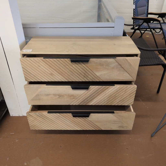 Wooden drawer unit with a striped pattern on a brown floor.