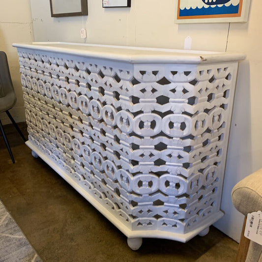 Decorative white lattice cabinet in a room setting with furniture and decor.