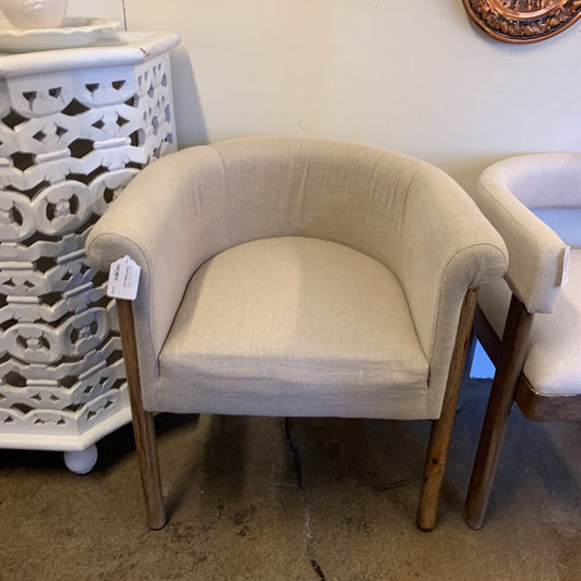 Beige upholstered chair with wooden legs in a room setting