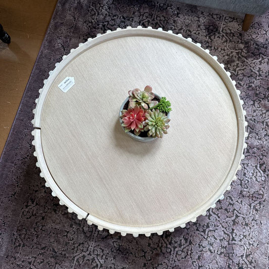 Round wooden table with a small potted succulent on a textured surface