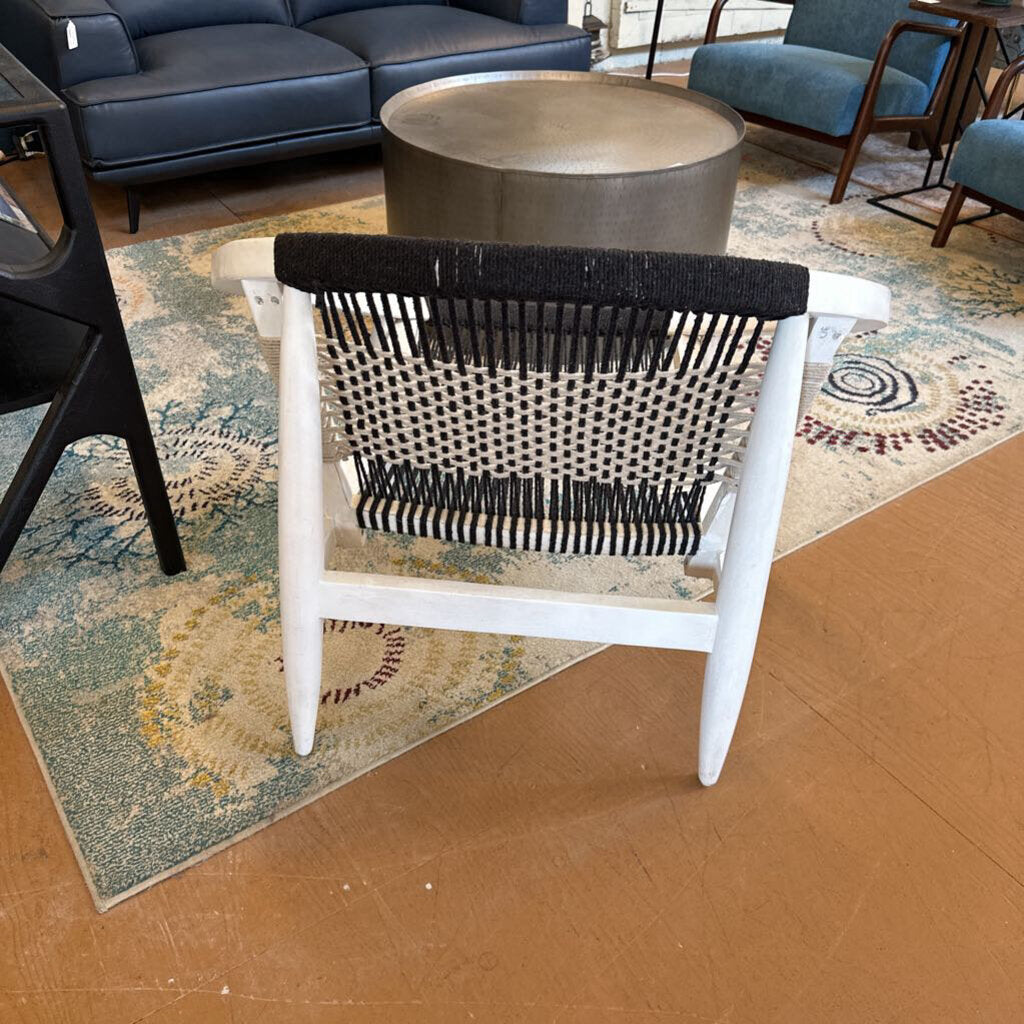 White chair with black woven backrest on a patterned rug in a living room setting
