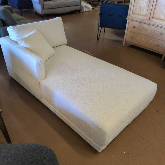 White textured chaise lounge in a room with wooden floor and furniture.