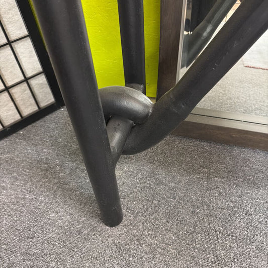 Close-up of a black metal chair leg on a gray carpeted floor.
