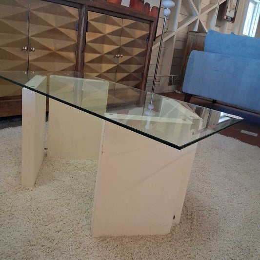 Glass-top dining table with white base in a room with furniture and decor.