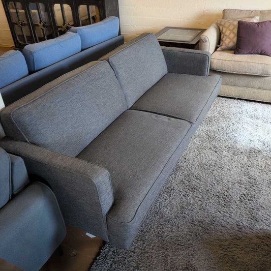 Gray sectional sofa in a living room setting with other furniture.