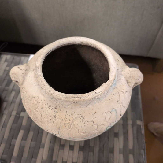 Ceramic vase with two handles on a textured surface