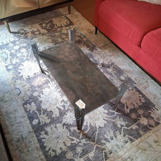 Dark metal bench on a patterned rug with a red couch in the background