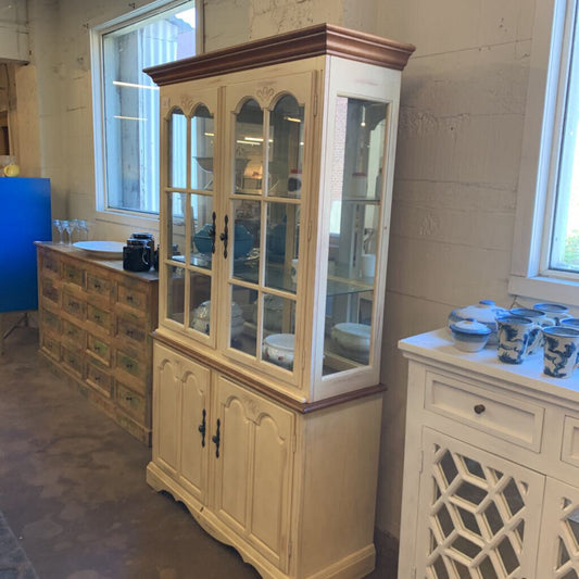 Large glass-fronted cabinet in a room with other furniture and decor.