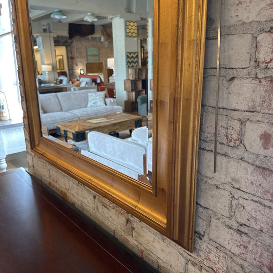 Large wooden-framed mirror on a brick wall