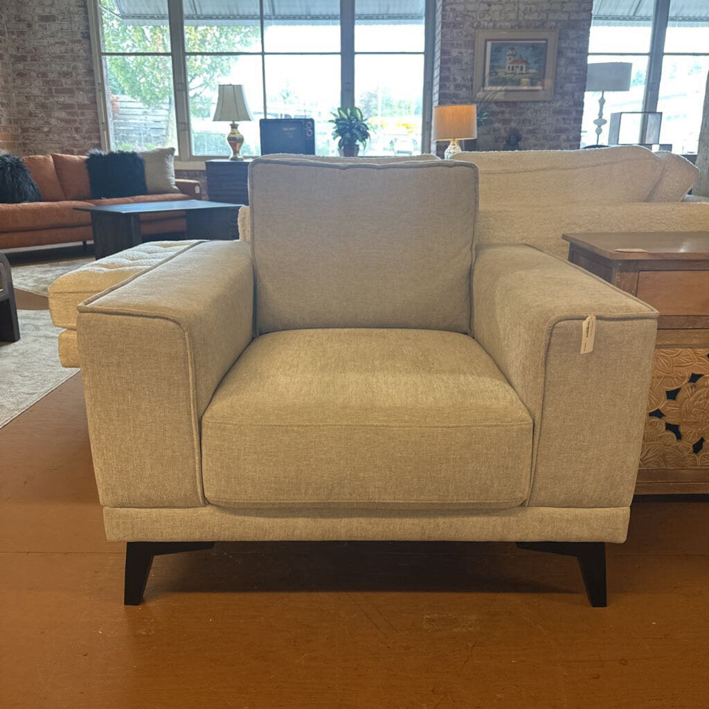 Beige armchair in a living room setting with furniture and decor.