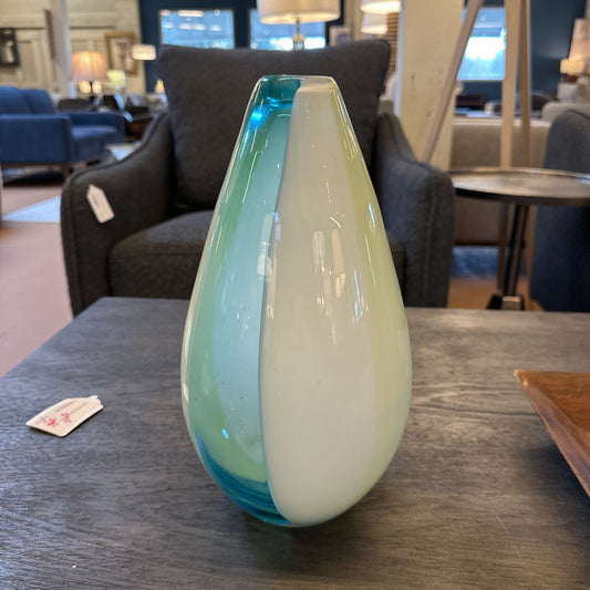 Two-toned glass vase on a table with a blurred indoor setting