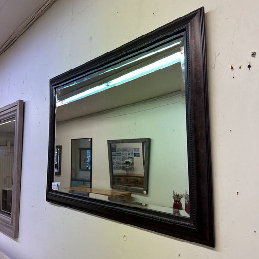 Large mirror with a dark wooden frame on a white wall
