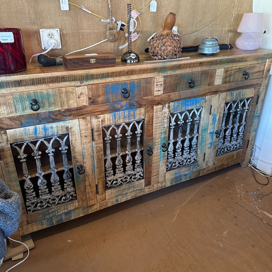 Wooden sideboard with decorative metal panels on a wooden floor.