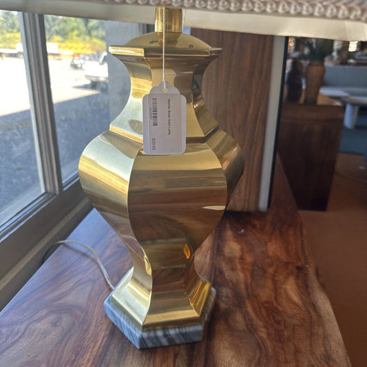 Gold lamp with a tag on a wooden surface near a window