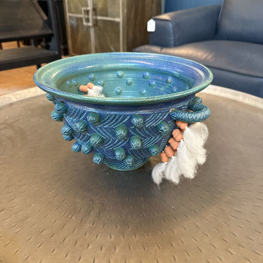 Blue textured bowl with a small gnome figure on a metallic surface