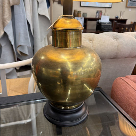 Brass table lamp on a glass surface with a blurred indoor setting