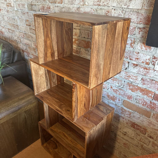 Wooden bookshelf against a brick wall