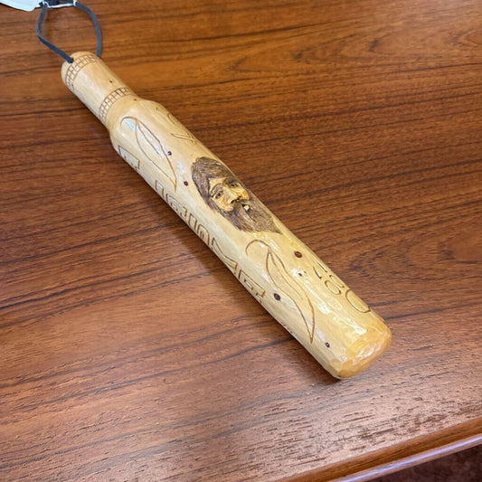 Wooden flute with engraved face on a wooden surface