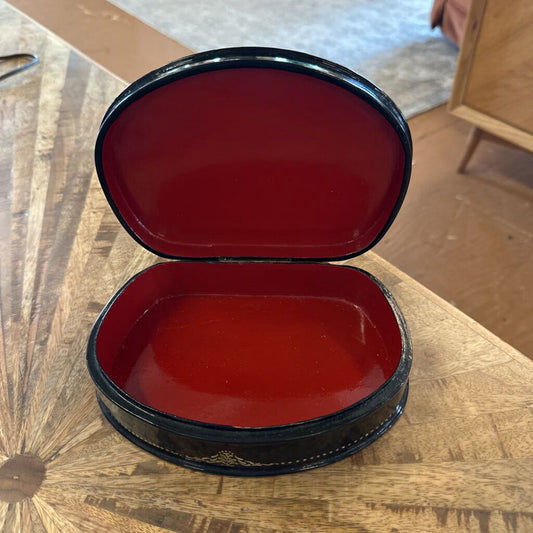 Red and black oval jewelry box on a wooden surface