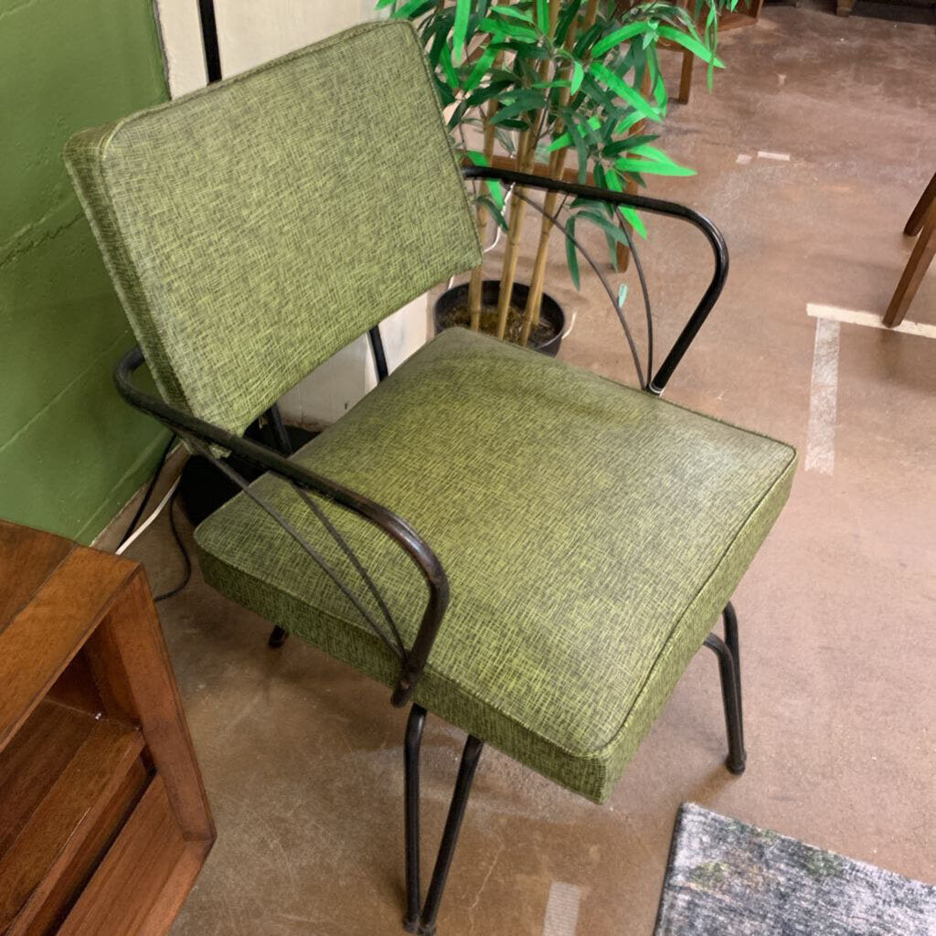 Green chair with black metal frame on a tiled floor