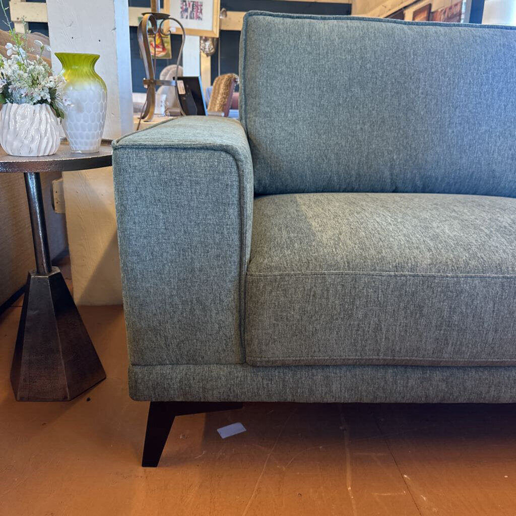 Gray sofa in a room with a wooden floor and decorative items.