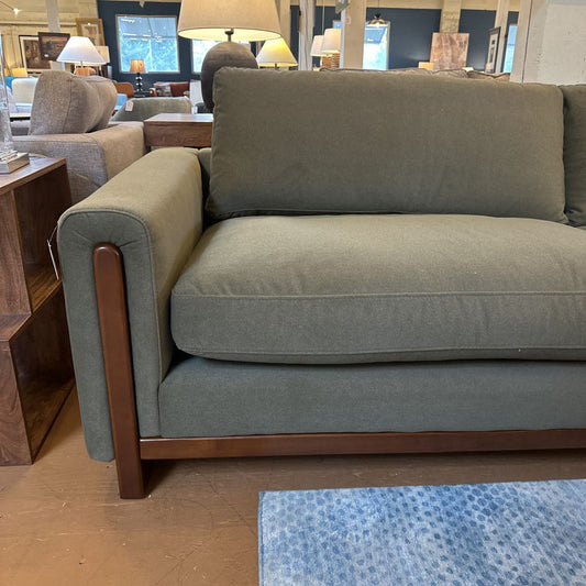 Gray sofa with wooden armrests in a showroom setting